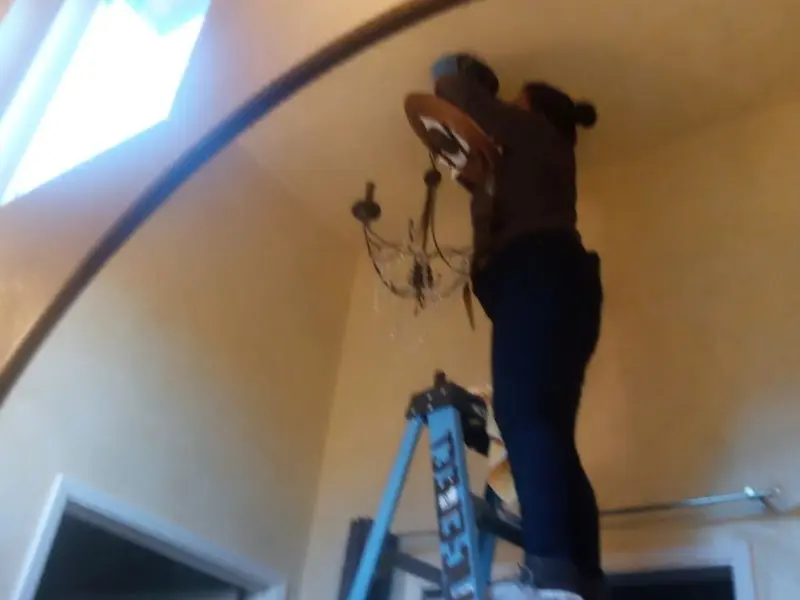 Electrician installing a chandelier in a Blackhawk residence